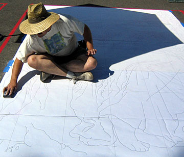 Wayne works powdered chalk through the holes in the paper to transfer traced lines to the pavement