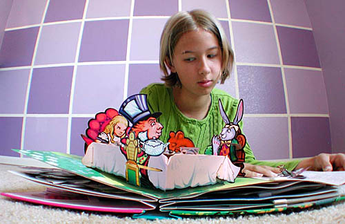 Original photo of Alex looking at an Alice In Wonderland pop-up book