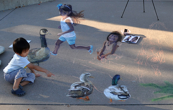 A toddler poses with the painting and points out the ducks